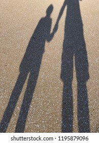Shadow of a father holding hands with his kid.
