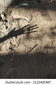 Shadow of a female hand on the ground with a shoe print.