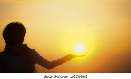 Shadow of the girl raise her hand and handle the sun with golden sky in the morning for copy space and background texture concept - Shutterstock ID 1631366662