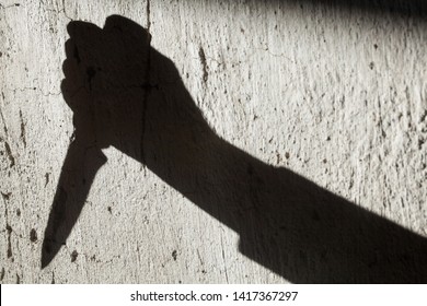 Shadow of the hand holding a big sharp knife. Murderer, killer or robber with a knife. Criminal. Crime. Horror scene.