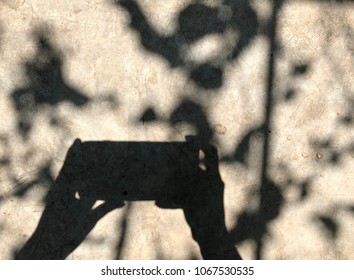Shadow of hand using mobile phone in bright sunlight