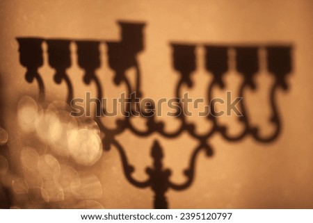 Shadow of Hanukkah menorah, or hanukkiah. Jewish holiday Hanukkah background. Shadow of Hanukkah lamp, nine-branched candelabrum without candles is out of focus. Selective focus.