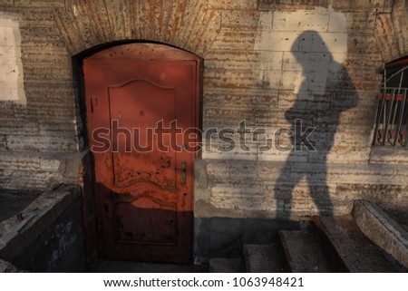 Shadow of human try to open the old red door