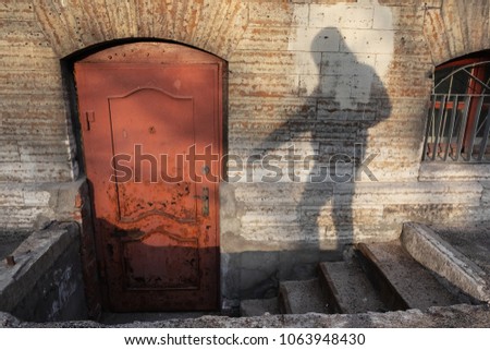Shadow of human try to open the old red door