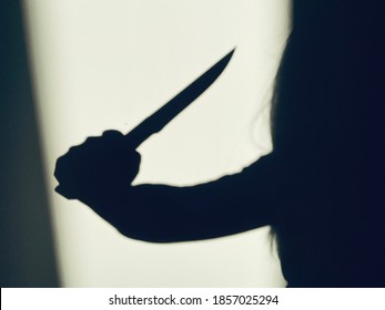 Shadow of killer with sharp knife on wall background