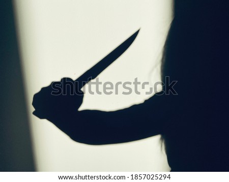 Shadow of killer with sharp knife on wall background