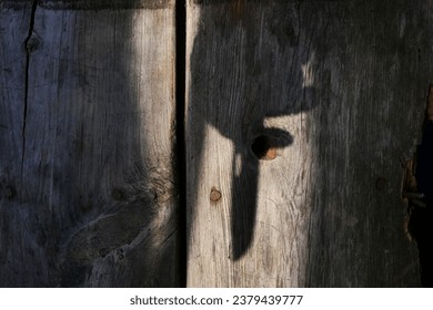 shadow of a knife in a man's hand on a wooden background