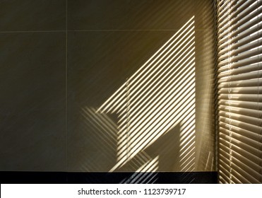 Shadow And Light Through Blinds Window On Tiled Wall. Abstract Form Morning Light And Shadow On The Wall.