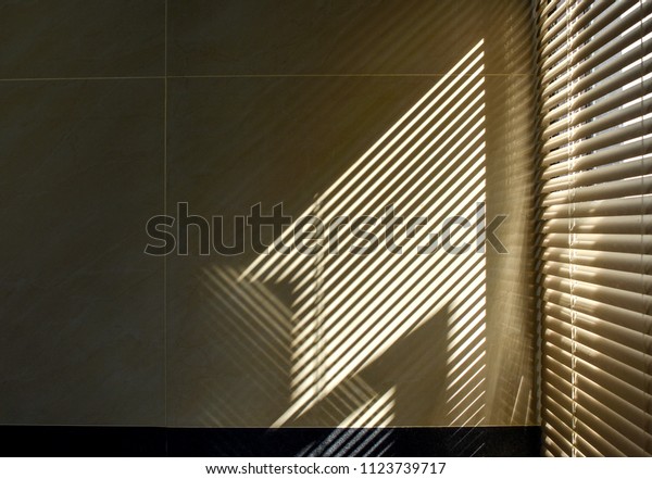タイル張りの壁のブラインドウィンドウを通る影と光 抽象的なフォームの朝の光と壁の影 の写真素材 今すぐ編集 1123739717