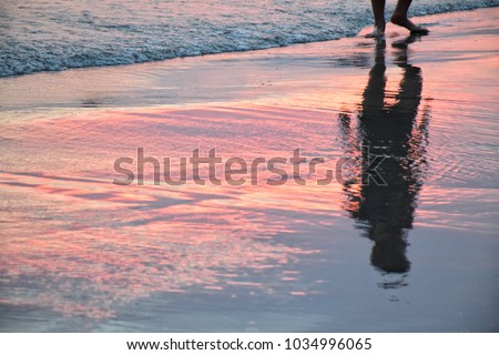 shadow of man in beautiful light sunset at the shoreline