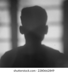 Shadow of a Man cast on wall by bright light coming from window of room - black and white filter strange alone scary - Powered by Shutterstock