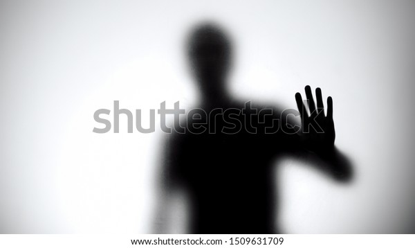 Shadow of man holding glass wall, trying to\
escape from captivity,\
kidnapping