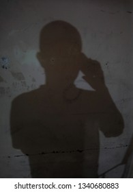 A Shadow Of A Man Holding A Mobile Phone Close To His Ear, Talking On Phone. 