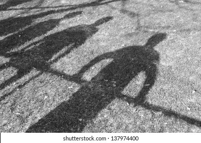 Shadow of man and kids leaning and sitting on fence.