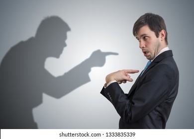 Shadow of man is pointing and blaming businessman. Conscience concept.