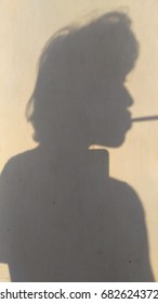 shadow of a man smoke.on a surface wall.