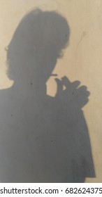 shadow of a man smoke.on a surface wall.