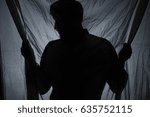 Shadow of a man standing behind the drape