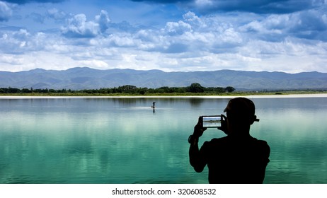 The Shadow Of A Man Using Smart Phone Photography Fisherman On The Lake .