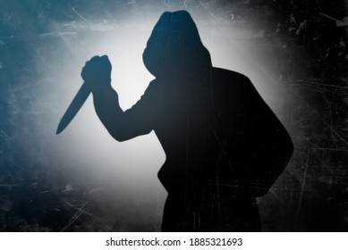 Shadow of the murderer holding the murder weapon. Silhouette of man with a knife in his hand