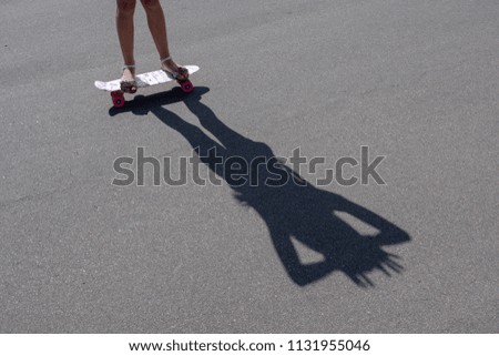 Shadow on the gray asphalt from a girl with a skate