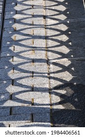The shadow on the ground from the parapet. On the stone embankment on a sunny day, the shadow of the embankment fence is reflected.