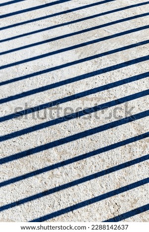 Shadow of parallel lines on a cement surface as abstract background 