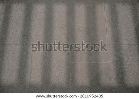 Shadow patterns on concrete pavement or wall tiles.