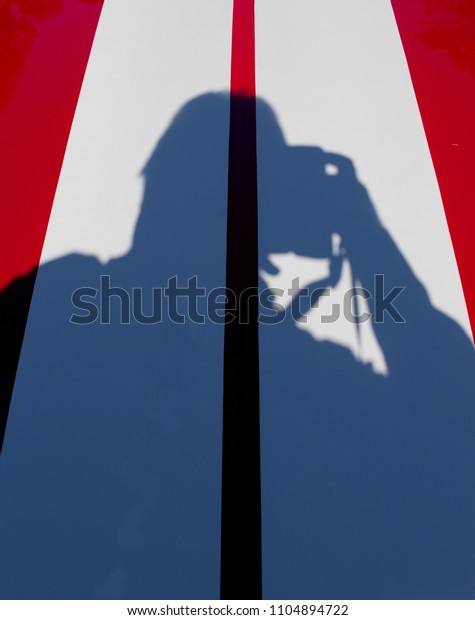 Shadow of a\
photographer on the red and white bonnet of a muscle car image with\
copy space in portrait\
format