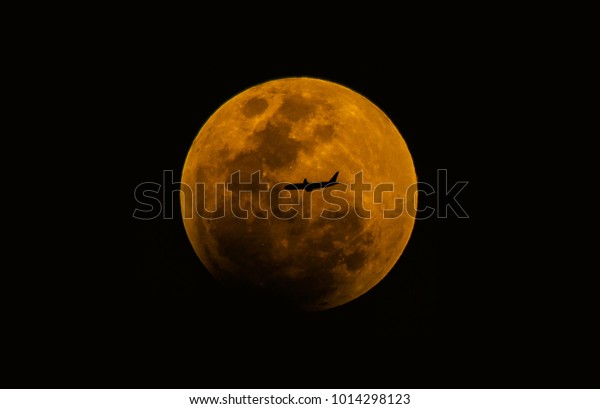 Shadow plane flying\
through the full moon.