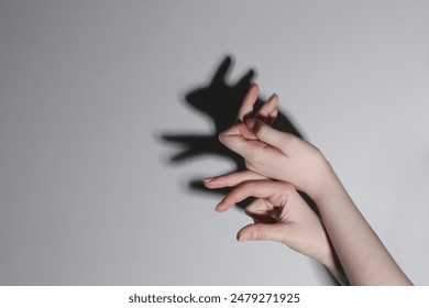 Shadow puppet. Woman making hand gesture like rabbit on grey background, closeup. Space for text - Powered by Shutterstock