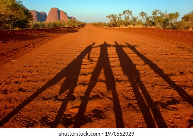 Shadow Selfie Of People Arms Raised On A Red Dust Road In The Outback Of Australia With Rock Formation Of Kata Tjuta Or Olgas In The Back; People Shadows Travel The World