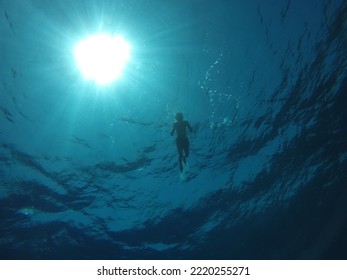 Shadow silhouette in black and dark blue color in red sea of a young man practicing snorkeling in the depths of the Red Sea - Powered by Shutterstock