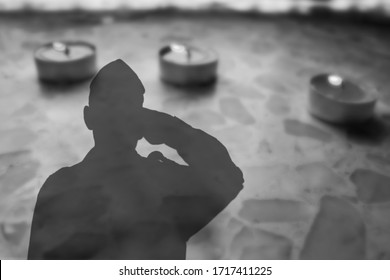 Shadow of a soldier Israel Defense Forces, IDF with salutes on Headstone , on Monument on cemetery, with burning funeral candles. Image for Memorial day Yom ha Zikaron or Yom ha Shoah