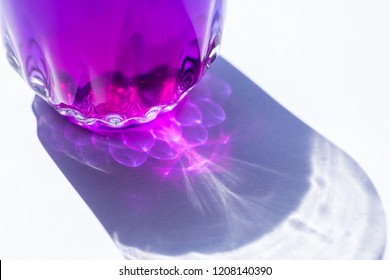 the shadow of sunlight reflect to glass of purple color water on white background.