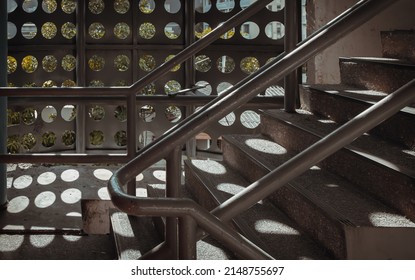 Shadow Of The Sunlight Streams That Shine Through The Circle Hole In The Metal Plate Of The Building Onto Fire Escape. Selective Focus.