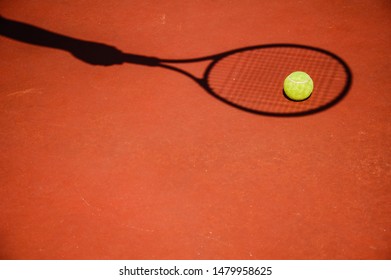 shadow of a tennis player's hand with a racket on the background of a tennis court