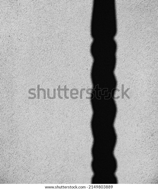 shadow\
of turned column cast onto textured outdoor exterior cement plaster\
or concrete home grey wall vertical format room for type black and\
white vertical backdrop background or wallpaper\
