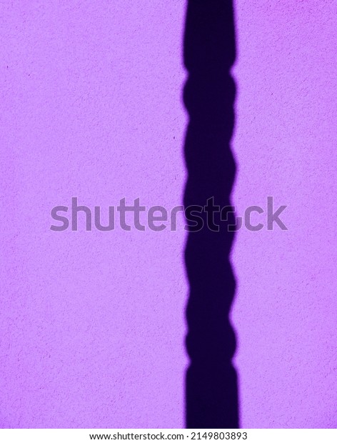 shadow\
of turned column cast onto textured outdoor exterior cement plaster\
or concrete home pink wall vertical format room for type vertical\
pink and black backdrop background or wallpaper\
