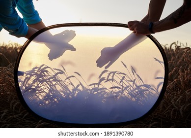 Shadow of two male hands, showing dog and eagle shapes in front of pale yellow sky at sunset.Shadow play with hands at natural background. Summer leisure entertainment.