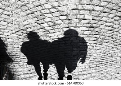 Shadow of a two men walking on cobbled pavement - sett pedestrian path , in black and white