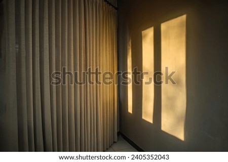 the shadow of the window on the wall with the window covered with curtains in the morning