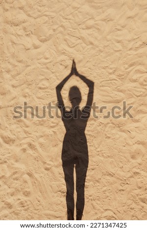 shadow of woman meditates and does yoga on sandy beach, sports and fitness outdoor on seashore. shadow and light silhouettes