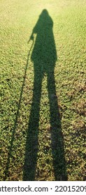 Shadow Of A Woman Standing Tall With A Cane.