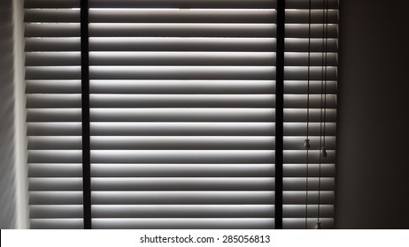 Shadow from wooden Venetian blind with drawstring.