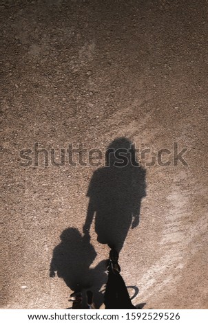 Shadow of a young mother and her child walking on the asphalt road. Happy mother's day