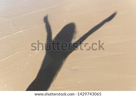 Shadow of a young woman happy to be on the beach.