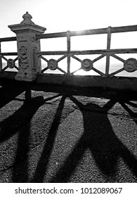 Shadows cast by the setting Sun, metal railings on Brighton seafront. Brighton, England.