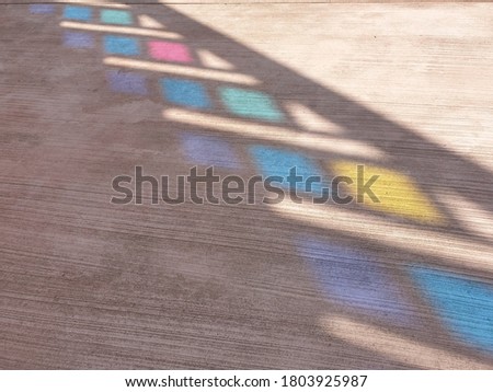 The shadows of the colorful stained glass are reflected on the ground