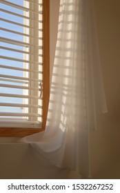 Shadows Of The Evening Sun Coming Through Window Blinds Leaves A Soft Shadow On Draped Sheer Linen Curtains